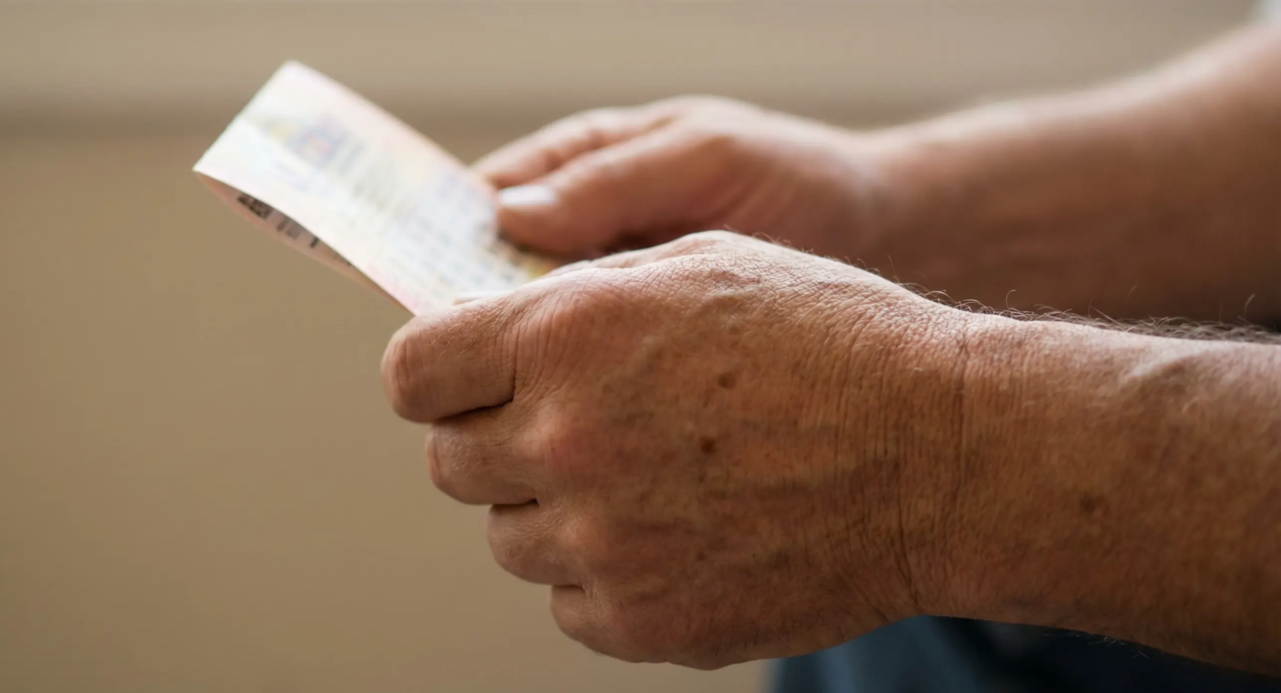 M&atilde;os a segurar um bilhete de lotaria com esperan&ccedil;a